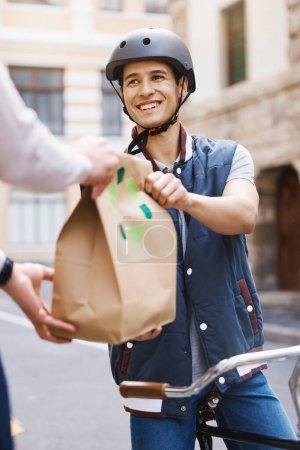 Photo for Man, delivery bicycle and smile with bag, order or e commerce for food, product or sustainable transport. Young guy, bike and cbd street for customer experience, chat or eco friendly at logistics job. - Royalty Free Image