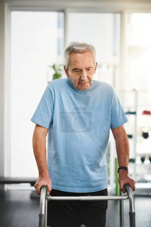 Foto de Cada día me acerca un paso más a una mejor salud. un hombre mayor usando un andador en un centro de rehabilitación - Imagen libre de derechos