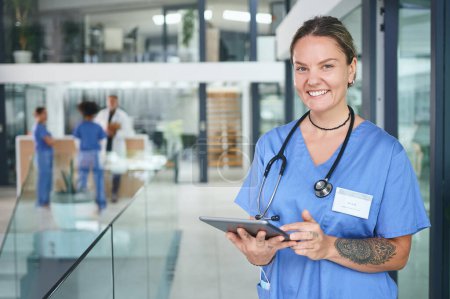 Photo for Not all heroes wear capes, some wear scrubs. Cropped portrait of an attractive young nurse standing and using a digital tablet in the clinic - Royalty Free Image