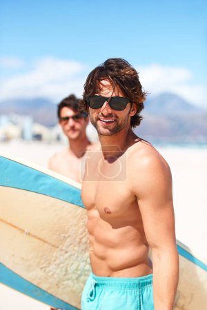 Beach, ocean and man surfing friends outdoor together for travel, vacation or holiday trip overseas. Surf, summer or fun with a young male surfer in sunglasses and friend bonding by the sea or coast.
