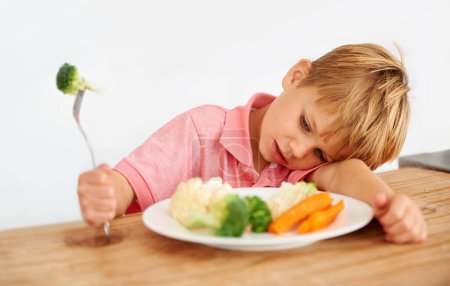 Photo for Sad, diet and a child with vegetables for dinner, unhappy meal and problem with food. Frustrated, hungry and dislike of boy kid eating broccoli, carrots and disappointed with healthy lunch at home. - Royalty Free Image