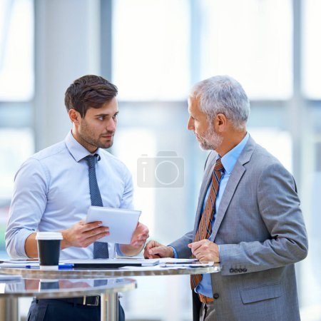 Photo for Discussion, tablet and business development team talking and in collaboration in a meeting for online information. Together, mentor and senior businessman coaching young person in training for job. - Royalty Free Image
