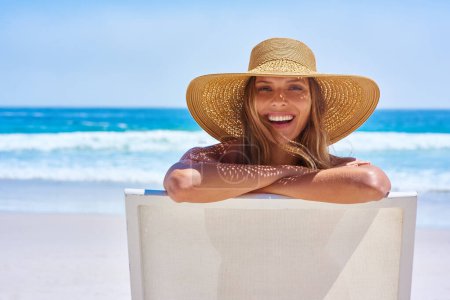 Photo for Portrait, beach and woman with a smile, holiday and summer getaway with tourism, break or travelling. Face, female person or girl on a chair, seaside vacation or travel with a hat or relax with waves. - Royalty Free Image