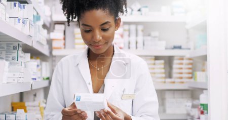 Foto de Esto funcionará perfectamente para ella. un joven farmacéutico atractivo mirando una caja de medicamentos en un químico - Imagen libre de derechos
