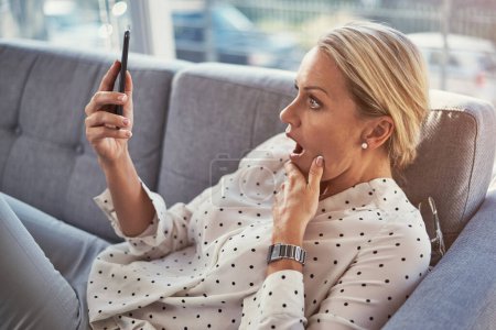 Photo for I got all this data for that price. a mature woman using her cellphone while relaxing at home - Royalty Free Image