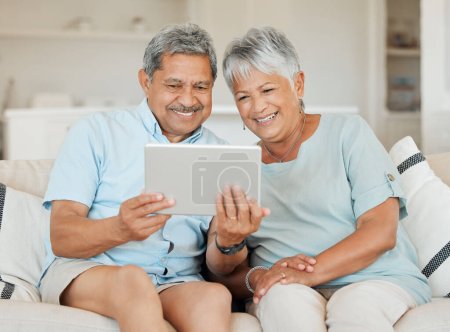 Foto de Tecnología, pareja casada con tableta y sonrisa en el sofá en la sala de estar de su casa. Conectividad, redes sociales y feliz con las personas mayores en el sofá streaming de una película en el sofá de la casa. - Imagen libre de derechos