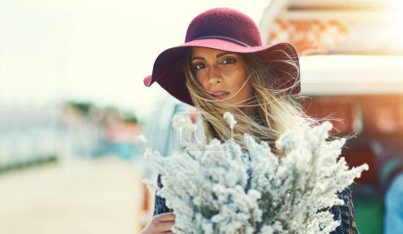 Foto de Bonita como una flor silvestre. Retrato de una mujer joven parada afuera con un ramo de flores silvestres - Imagen libre de derechos