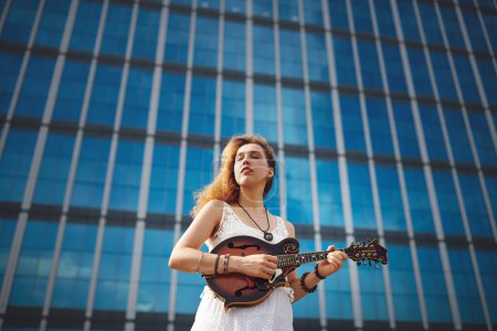 Foto de Ve a donde te lleve la música. una hermosa joven en la ciudad con su guitarra - Imagen libre de derechos