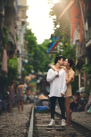 Foto de El tipo de romance con el que soñamos. una joven pareja compartiendo un momento romántico en las vías del tren en las calles de Vietnam - Imagen libre de derechos