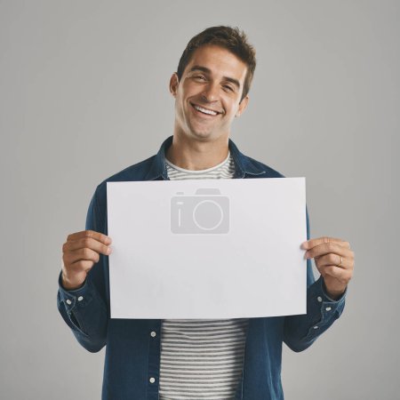 Photo for Its time to tell your story. Studio portrait of a young man holding a blank placard against a grey background - Royalty Free Image