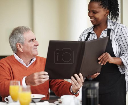 Waitress, menu and senior man in a restaurant for breakfast or lunch at a hotel with service and choice of food. Friendly, order and elderly person happy on vacation or holiday for hospitality.