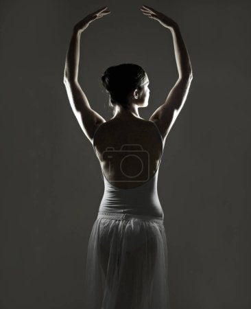 Foto de Arte, silueta y espalda de una bailarina de ballet en un estudio con elegante postura, pose o posición. Bailarina creativa, monocromática y femenina haciendo una danza clásica o actuación con fondo negro - Imagen libre de derechos