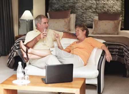 Photo for Retirement, love and an old couple drinking wine in their hotel room while on holiday or vacation together. Toast, sofa or relax with a senior man and woman bonding at a luxury resort for romance. - Royalty Free Image