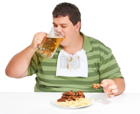 Téléchargez les photos : Obésité, l'homme et la restauration rapide avec de l'alcool, malsain et le gars isolé sur un fond de studio blanc. Obèse, homme et mannequin avec bière, ailes de poulet et manger avec un bavoir, frites et faim. - en image libre de droit
