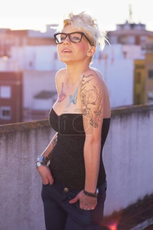 Foto de Fresco, elegante y retrato de una mujer con tatuajes, estilo único y creatividad en la ciudad. Moda, creativa y una dama con ropa de moda, punk y urbana en una azotea para la moda y el verano. - Imagen libre de derechos