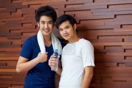 Photo for Happy, portrait and gay couple at the gym with water on a break from a workout together. Smile, wellness and Asian lgbt men training at a club for exercise, health and happiness with fitness. - Royalty Free Image