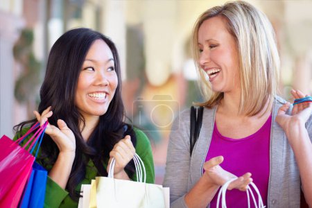 Téléchargez les photos : Heureux, la vente et les femmes avec des sacs de shopping dans la ville ou le centre commercial et excité par un accord. Sourire, conversation et diversité avec des amies qui parlent dans un magasin de vêtements et de mode. - en image libre de droit