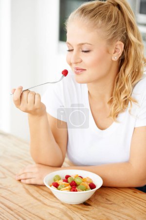 Photo for Fruit, wellness and woman eating healthy food for lunch or breakfast meal or diet in the morning in her home kitchen. Nutrition, health and vegan person smile and happy for salad, food and self care. - Royalty Free Image