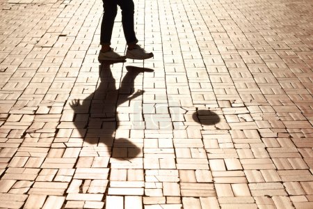 Foto de Deportes, fútbol y sombra de hombre con un entrenamiento de pelota para una habilidad, truco o truco en un pavimento. Silueta, fútbol y piernas de un hombre que practica un partido, partido o torneo en la ciudad - Imagen libre de derechos