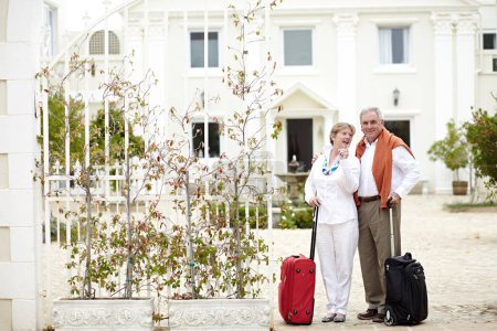 Foto de Viaje, hotel y pareja de personas mayores se relajan de vacaciones con la maleta en un lugar de vacaciones feliz en la jubilación juntos. Bolsa, sonrisa y personas mayores en un viaje o hombre y mujer señalando en la felicidad. - Imagen libre de derechos