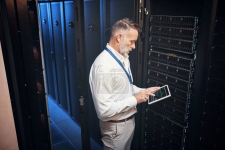 Foto de Su Internet no se quedará abajo con él alrededor. un hombre maduro usando una tableta digital mientras trabaja en una sala de servidores - Imagen libre de derechos