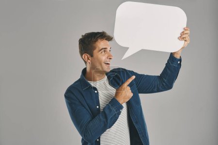 Photo for I just wanted to tell you this. Studio shot of a young man pointing to a speech bubble against a grey background - Royalty Free Image