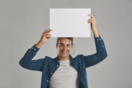 Photo for Heres the big news. Studio portrait of a young man holding a blank placard against a grey background - Royalty Free Image
