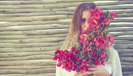 Can you guess what the secret to her beauty is. an attractive young woman holding a bunch of fresh flowers