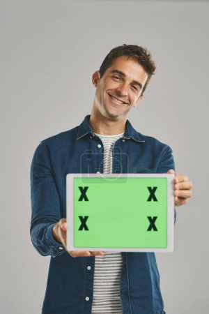 Photo for Its the website I visit every day. Studio portrait of a young man holding a digital tablet with a green screen against a grey background - Royalty Free Image