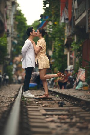 Foto de Un amor como el de ellos es difícil de encontrar. una joven pareja compartiendo un momento romántico en las vías del tren en las calles de Vietnam - Imagen libre de derechos