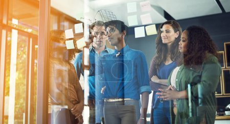 Photo for Strive for progress above simply perfection. a group of businesspeople brainstorming with notes on a glass wall in an office - Royalty Free Image