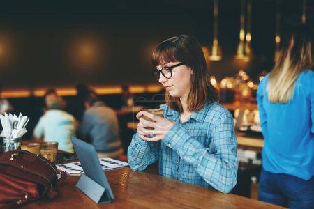 Téléchargez les photos : Wifi gratuit signifie streaming sans fin. une jolie jeune femme utilisant une tablette numérique dans un café - en image libre de droit