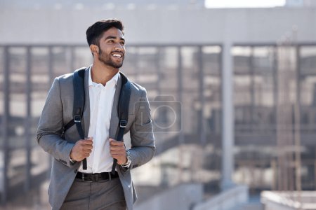 Foto de Viaje, feliz y hombre de negocios caminando por la ciudad a su edificio de oficinas por la mañana. Confianza, mochila y empleado masculino profesional con una sonrisa viajando al trabajo en una calle urbana - Imagen libre de derechos