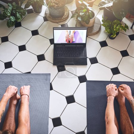 Foto de Los tiempos de cambio requieren un poco de flexibilidad. dos hombres usando un ordenador portátil mientras pasan por una rutina de yoga en casa - Imagen libre de derechos