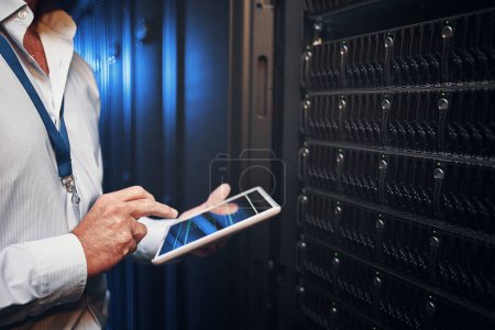 Photo for Cyber security made super simple. an unrecognisable man using a digital tablet while working in a server room - Royalty Free Image