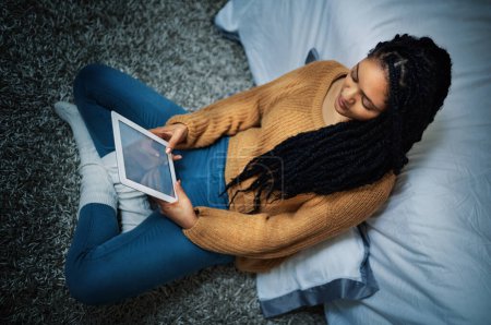 Foto de Tiempo de inactividad digitalizado. una mujer joven y relajada usando una tableta digital durante la noche en casa - Imagen libre de derechos