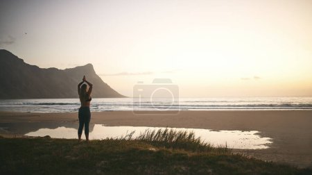 Photo for I do yoga every day. Full length shot of an unrecognizable woman standing alone and meditating during a relaxing day outdoors - Royalty Free Image