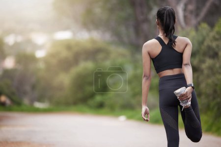 Photo for Nature, woman and warm up from back, workout motivation and fitness while stretching legs. Dedication, commitment and girl runner standing on road with leg stretch for outdoor run and exercise goals - Royalty Free Image
