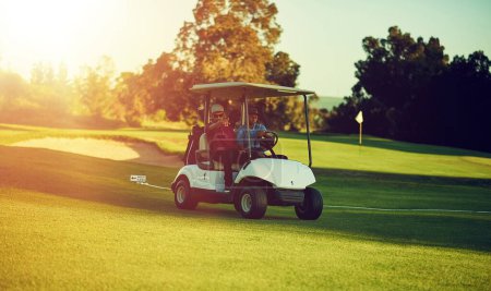 Téléchargez les photos : Monter où l'herbe est plus verte. deux golfeurs en chariot sur un terrain de golf - en image libre de droit