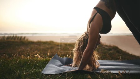 Foto de Mantén la calma y haz el yoga. una atractiva joven que sostiene una posición de perro boca abajo durante una sesión de yoga al aire libre - Imagen libre de derechos