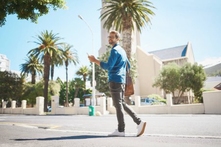 Photo for Theres so much to see around here. a handsome man using his cellphone while out in the city - Royalty Free Image