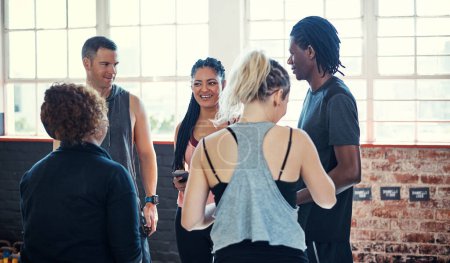 Photo for Some workout chit chat. a cheerful young group of people standing in a circle and having a conversation before a workout in a gym - Royalty Free Image