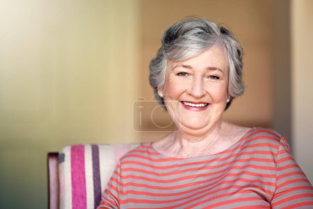 Téléchargez les photos : Maison, détente et portrait d'une femme âgée avec un sourire pour la retraite et le bonheur des personnes âgées. Joyeux, relaxant et une dame âgée dans une chaise dans le salon avec confiance et confort. - en image libre de droit