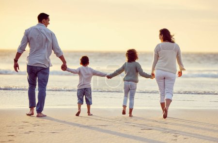 Photo for Walking, beach and back of family holding hands on holiday, summer vacation and weekend at sunset. Nature, travel and mother, father and children by ocean for bonding, adventure and quality time. - Royalty Free Image
