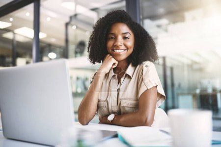 Téléchargez les photos : Le sourire du succès. Portrait d'une jeune femme d'affaires utilisant un ordinateur portable à son bureau dans un bureau moderne - en image libre de droit