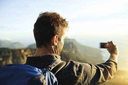 Téléchargez les photos : Faire des souvenirs est la meilleure partie. un jeune homme faisant des selfies en montant une montagne - en image libre de droit