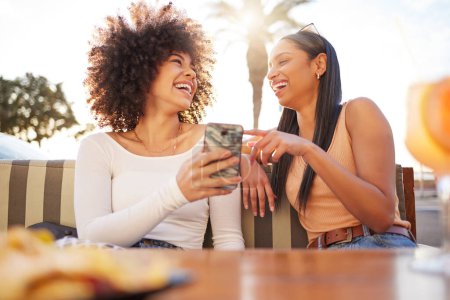 Photo for Laughing, happy and women with a phone at a cafe for a meme or social media notification. Smile, talking and friends with a mobile for a funny app, comic conversation or comedy together at restaurant. - Royalty Free Image