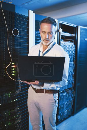 Photo for Lets get this internet running at top speeds. a mature man using a laptop while working in a server room - Royalty Free Image