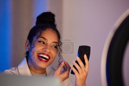 Photo for Influencer woman, ring light and eyeshadow with smile, cosmetics or beauty on live stream, broadcast or web video. Girl, review or online entrepreneur with happiness, mirror and comic on social media. - Royalty Free Image