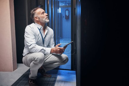 Photo for Hell help you connect those wifi dots. a mature man using a digital tablet while working in a server room - Royalty Free Image